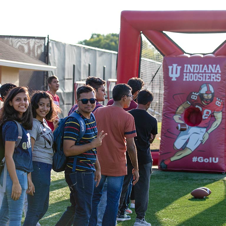 Students stand in line to participate in a football toss game