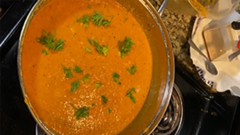 A pot of Indian chicken tikka masala sits on a stove.