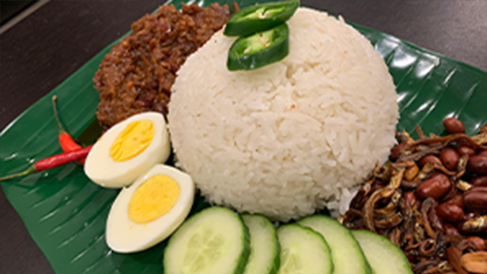 A plate of Nasi Lemak, a Malaysian cuisine, with hard boiled eggs and cucumber slices.